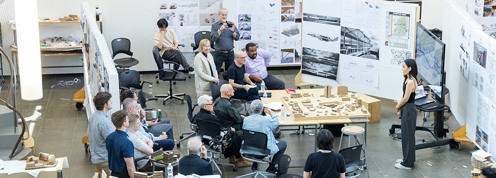 Students and jury gather around Portman Studio poster work