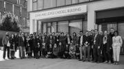 Black-and-white group photo of people standing outside a building. The name on the building reads "John and Joyce Caddell Building."